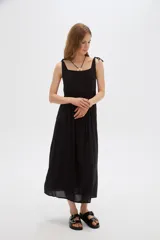Vestido midi negro de viscosa con cuello cuadrado y tirantes finos ajustables con lazo en los hombros, de corte holgado y diseño fluido.