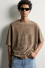 Remera relaxed fit color marrón con cuello redondo, manga corta y parche bordado a tono con letras en el frente.