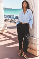 Pantalón verde oliva de lino con tiro alto, pinzas delanteras, bolsillos frontales y falsos bolsillos con solapa en la espalda. Incluye cinturón marrón y cierre delantero con cremallera, botón interior y gancho.