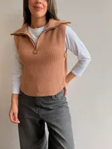 Chaleco de tejido de punto acanalado en color camel, con cuello polo, medio cierre frontal y aberturas laterales con detalle de botones.