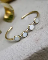 Pulsera rígida dorada con cuatro piedras redondas de nácar engarzadas.