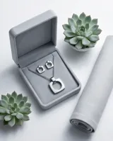 Set de joyería compuesto por un collar con cadena de eslabones y dije cuadrado con centro circular, y aros colgantes a juego con el mismo diseño geométrico. Realizado en acero inoxidable con acabado pulido.