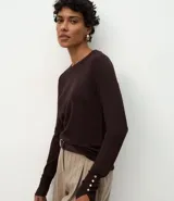 Suéter de punto ajustado con cuello redondo y manga larga. Presenta detalle de botones metalizados en los puños.