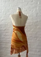 Vestido corto con estampado abstracto en tonos naranja, blanco y marrón. Diseño con escote halter y espalda descubierta.