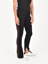 Pantalón negro con franja lateral marrón, cintura elástica con cordón ajustable, bolsillos laterales con cierre y cierres en los tobillos.