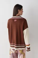 Cardigan de punto color chocolate con diseño de bloques de color y detalles a rayas en cuello, puños y ruedo. Presenta cierre frontal con botones, cuello tipo polo y dos bolsillos delanteros.