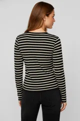 Remera de manga larga con cuello redondo y abertura frontal con botones. Presenta un patrón de rayas horizontales blancas y negras, y un pequeño bolsillo negro en el pecho.