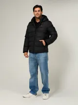 Campera puffer Tommy Hilfiger de color negro, acolchada con diseño horizontal, capucha integrada y cierre frontal de cremallera. Cuenta con bolsillos laterales con cierre y el logo bordado en el pecho.