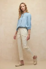 Pantalón color beige de algodón, tipo paper touch, con elástico en la cintura y cordones. Tiene un fit recto con bolsillos de solapa y botones a tono.