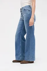 Jean de corte wide leg con tiro medio y cierre frontal con botones a la vista. Presenta un diseño holgado desde la cadera hasta el bajo con pierna ancha.