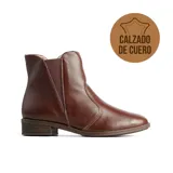 Bota baja de cuero color marrón, con diseño tipo chelsea que incluye paneles elásticos laterales y taco bajo cuadrado.