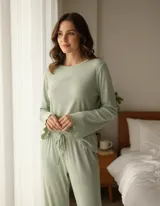 Pijama de dos piezas en color verde menta, confeccionado en tejido modal acanalado. La parte superior es una remera de manga larga con terminaciones onduladas en los puños y un pequeño bordado de corazón en el pecho. El pantalón es de corte recto con cintura elástica y cordón ajustable.
