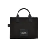 Bolso tipo tote Marc Jacobs modelo The Cargo Canvas Medium, color negro. Confeccionado en lona resistente, cuenta con asas superiores, correa ajustable para el hombro y múltiples bolsillos delanteros externos. Presenta el texto "THE TOTE BAG" y el logo de la marca bordados en el frente.