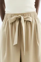 Pantalón color beige de corte amplio, con cintura elástica y lazo para atar. Confeccionado en sarga de mezcla de modal, con bolsillos laterales y un bolsillo decorativo atrás.