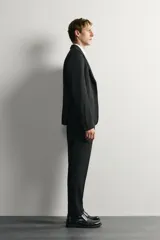 Blazer slim fit de Zara en color negro, confeccionado con mezcla de viscosa. Cuenta con cuello de solapas de muesca, cierre frontal de un botón, bolsillos con solapa en la cadera y un bolsillo de vivo en el pecho.