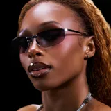 Lentes de sol con diseño envolvente y montura de acero inoxidable color plata. Presentan una barra superior metálica pulida que sujeta las lentes mediante remaches, con lentes de nylon en degradado gris y patillas con terminación en acetato.