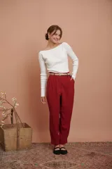 Pantalón de vestir color bordó, de corte recto, con pinzas en la cintura, pretina ancha y bolsillos laterales y traseros. Se ajusta a la cintura con cinturón trenzado dorado.