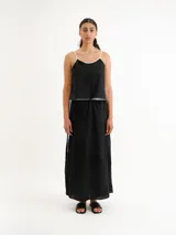 Vestido largo negro de tirantes finos blancos, corte recto y diseño minimalista.