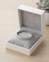 Esclava rígida de acero con acabado plateado y textura grabada con patrón geométrico.