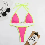 Bikini de dos piezas con corpiño triangular y bombacha colaless. El diseño destaca por sus detalles de cadenas doradas con perlas incrustadas en los breteles del corpiño y en los laterales de la bombacha. Presenta una combinación de colores vibrantes en amarillo y naranja.