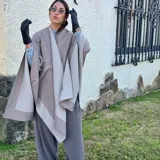 Ruana de material símil cachemira, de diseño bicolor en tonos gris y lila con bandas anchas en los bordes.