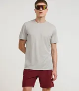 Bermuda deportiva gris con cintura elástica, cordón de ajuste, bolsillos con cremallera, recorte lateral con agujeritos y abertura en el bajo.