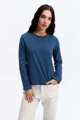 Remera de manga larga color beige, con cuello redondo y detalles calados decorativos en el borde del cuello y en los puños.