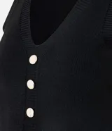 Chaleco sin mangas de tejido de punto negro, con escote en V y cierre frontal mediante una hilera de botones metálicos dorados.