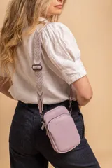 Bandolera compacta color rojo con textura de cuero, correa regulable y desmontable con diseño de rayas rojas y blancas. Cuenta con bolsillos frontales y cierre, interior forrado en tela.