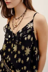 Top de tirantes finos en tejido jacquard negro con estampado floral metalizado dorado, escote con volados y diseño fluido.