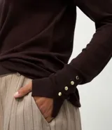 Suéter de punto ajustado con cuello redondo y manga larga. Presenta detalle de botones metalizados en los puños.