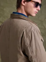 Campera de gabardina color azul marino, con cuello camisero, cierre frontal con botones metálicos y bolsillos frontales con solapa.