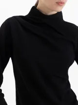 Sweater de lana merino color negro, con cuello medio alto y detalle de frunces en los hombros que aportan volumen. De calce regular y tejido suave.