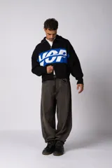 Campera tejida de punto con cierre frontal completo, cuello tipo polo y diseño con franja horizontal en contraste con estampado gráfico. Presenta puños y ruedo acanalados, con corte holgado.