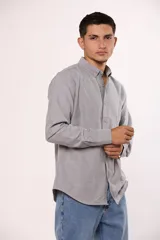 Camisa de manga larga en color gris, confeccionada en algodón, con cuello abotonado y cierre frontal de botones.