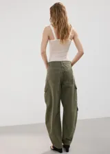 Pantalón cargo de jean color verde militar, de tiro medio, corte ancho y bolsillos laterales con solapa.