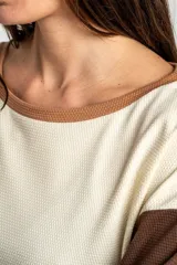 Sweater de algodón con diseño bicolor, cuerpo en color crema y mangas largas en color marrón oscuro. Presenta cuello redondo y un corte holgado tipo oversize.