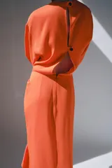 Vestido midi color naranja de la colección ZW de Zara, con cuello redondo, manga corta y detalle de tejido drapeado con volados en el delantero. Cuenta con cierre en la espalda con abertura y botón.