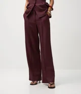 Pantalón de sastrería color bordó, modelo wide leg, con cintura alta y piernas amplias. Presenta cintura lisa con trabillas para cinturón, cierre delantero invisible, pliegues delanteros y bolsillos traseros embutidos.