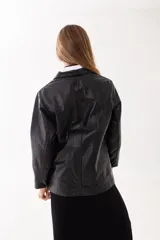Campera de cuero negro con cuello clásico, cierre frontal oculto y bolsillos laterales. Presenta un parche de cuero con el logo de la marca en la parte inferior.