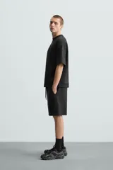 Bermuda de algodón color beige claro, corte relajado (relaxed fit), con cintura elástica ajustable mediante cordón y bolsillos laterales y trasero de plastrón.