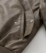 Campera bomber de poliuretano con acabado efecto cuero, cuello redondo, cierre frontal con cremallera, bolsillos delanteros y bolsillo utilitario en la manga. Presenta puños y ruedo elásticos, con forro interior en contraste.