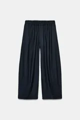 Pantalón de tiro medio con corte wide leg y cintura elástica ajustable. Presenta bolsillos laterales ocultos en las costuras y un diseño de pierna ancha con caída fluida.
