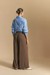 Pantalón ancho color marrón, de silueta moderna y calce cómodo, con diseño limpio y fluido. Presenta cierre frontal con botón y cordones ajustables en la cintura.