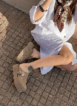 Zuecos color beige de gamuza con detalle de tachas y hebilla metálica.