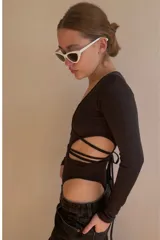 Body negro de lycra con mangas largas, escote pronunciado y aberturas en el torso unidas por tiras cruzadas.