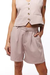 Short de vestir color rosa pálido, con pinzas delanteras, bolsillos laterales y cierre frontal con botón y cremallera.
