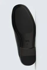Mocasín de piel color negro, con diseño minimalista de parte superior lisa, horma ligeramente cuadrada y suela ultrafina.