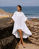 Vestido corto de lino color blanco, con mangas cortas amplias, escote redondo y diseño asimétrico más corto en la parte delantera y con volados en el ruedo.