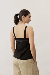 Musculosa de lino color negro con tirantes anchos de encaje y detalle de aplique metálico con la marca en la parte posterior.